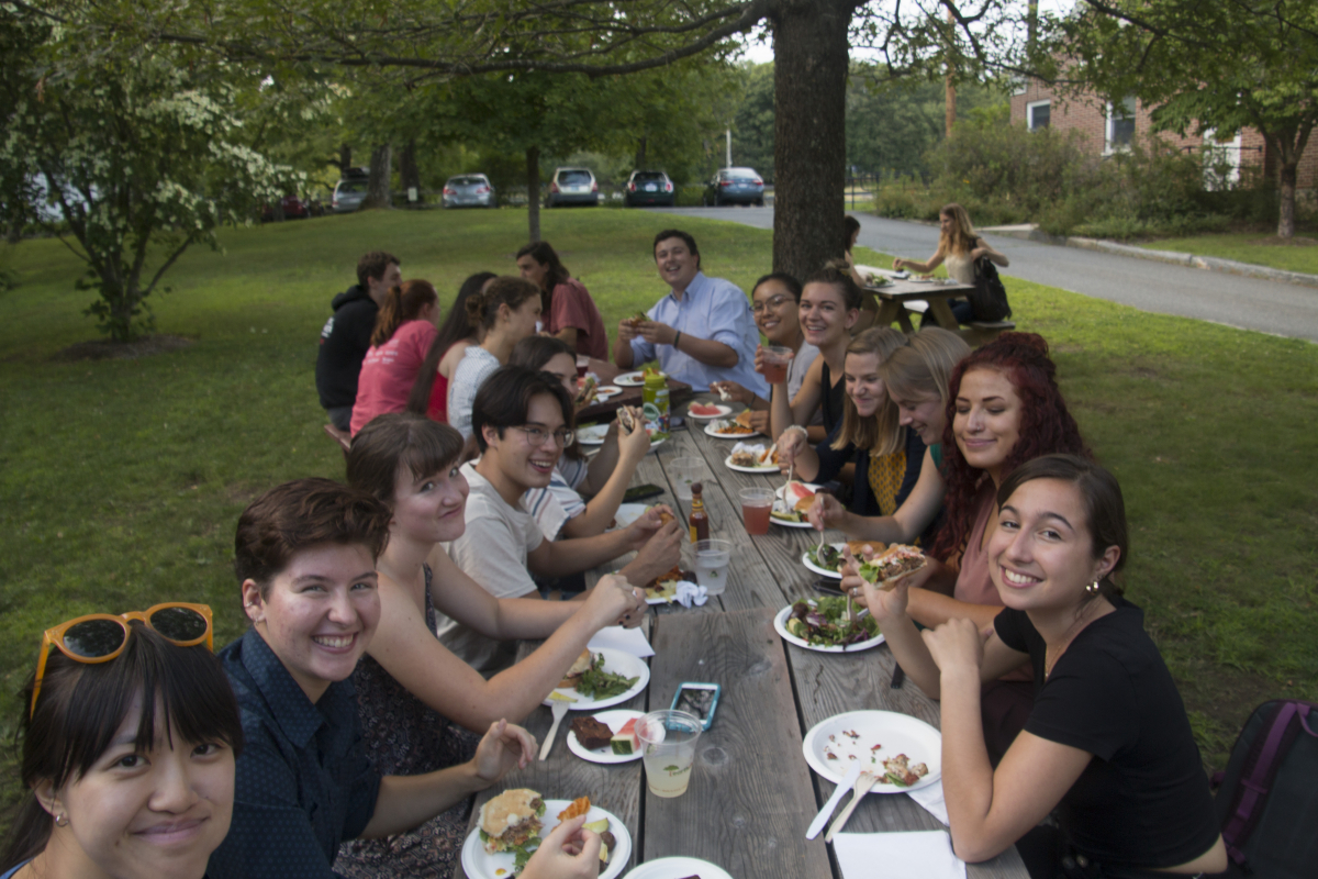 a group of 20 summer students sits at tables eating lunch