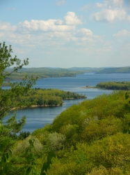 aerial view of the Quabbin Reservoir in early spring, with a blue sky and bright green leaves