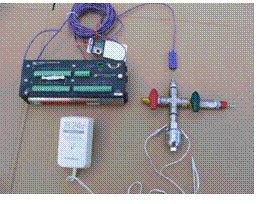 [Figure 1. Micro-bomb calorimeter (with electrodes from ignition unit) fitted to a stainless steel cross. Thermocouple inserted into top portion, connected to a datalogger. Quick-connect (right-side) for oxygen supply.]