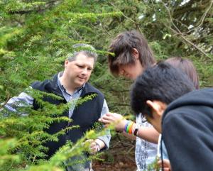 Ecologist Dave Orwig shows a hemlock branch to 3 high school students