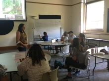 Dr. Elisa Margarita dialogues with a group of teachers seated at tables