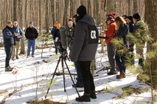 A dozen Harvard Forest scientists and a film crew stand in the snowy woods