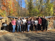 UMass students stand in front of newly stacked crates of firewood at the Petersham Wood Bank