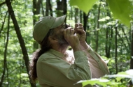 Aaron Ellison inspects and ant through a magnifying loupe in the forest in summer