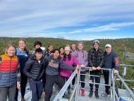 Photo shows 2023 Freshman Seminar students, instructor Dave Orwig, and guest Jackie Matthes atop a Harvard Forest research tower. 