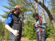 Two researchers in the woods looking at samples. 