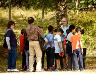 Image shows Pamela Snow, in teal/white shirt, giving a tour to students at Harvard Forest. 