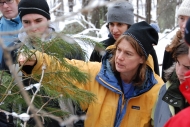 Missy Holbrook shows students a white pine tree in the forest in winter