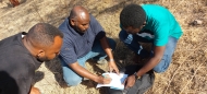 Image shows Ahmed Siddig, center, taking notes in the field