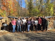 UMass students stand in front of newly stacked crates of firewood at the Petersham Wood Bank