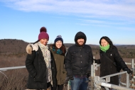 4 Harvard Forest winter interns from 2019 smile on top of the forest canopy tower