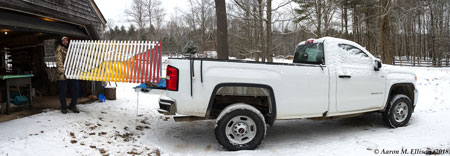 A man loads a wooden sculpture into the bed of a pickup truck