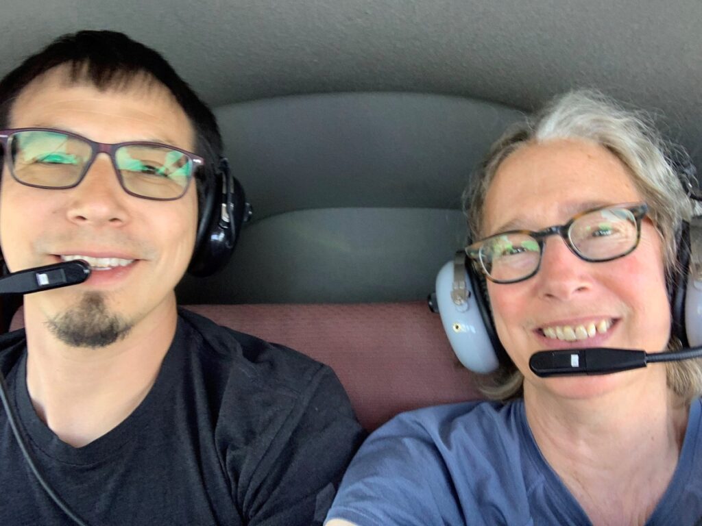 Two people wearing aviation headsets seated inside a small airplane