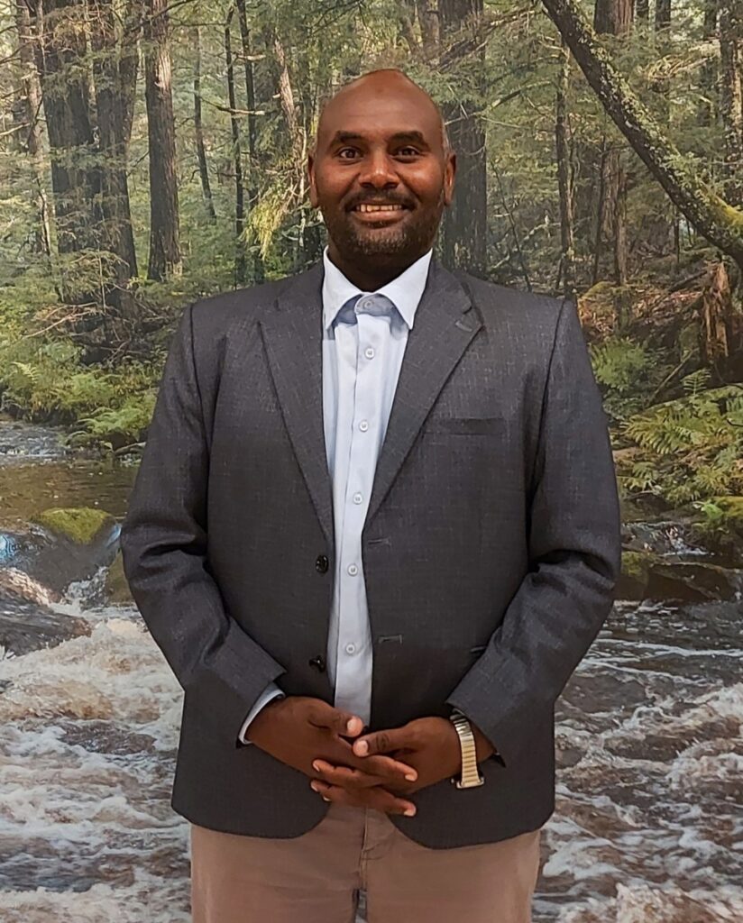 Ahmed Siddig standing in front of a photographic mural of a river