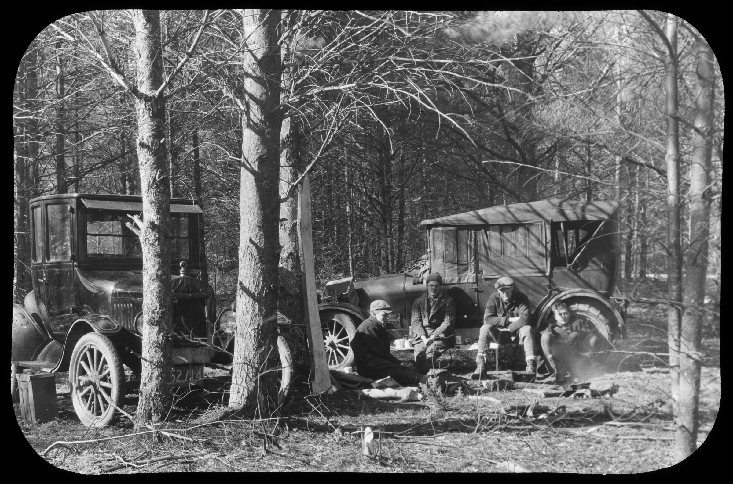 Four Harvard Forestry students taking a break in the field, lounging against their vehicle
