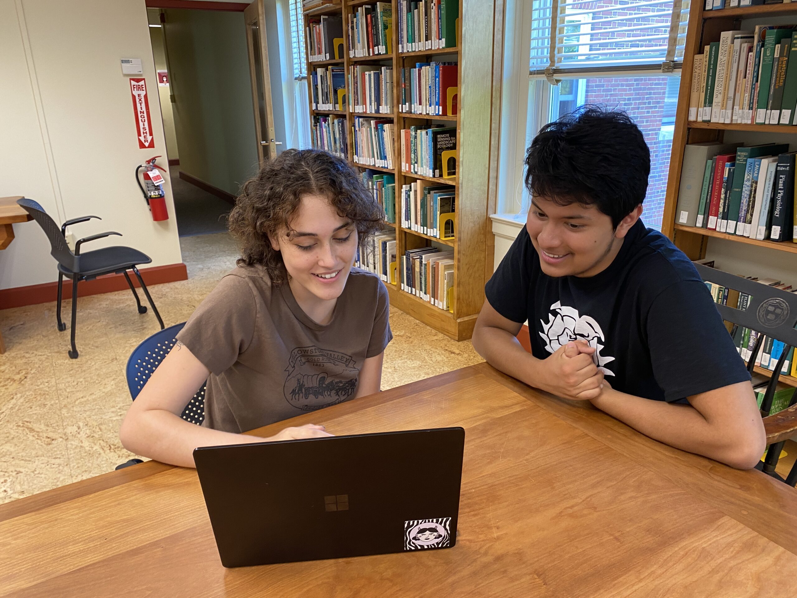 Image shows two interns discussing research at a table.