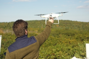 A researcher atop a research tower prepares to launch a drone over the forest canopy