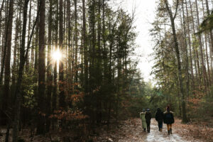 A small group of researchers walk through the forest in early spring, with the sun setting through the trees.